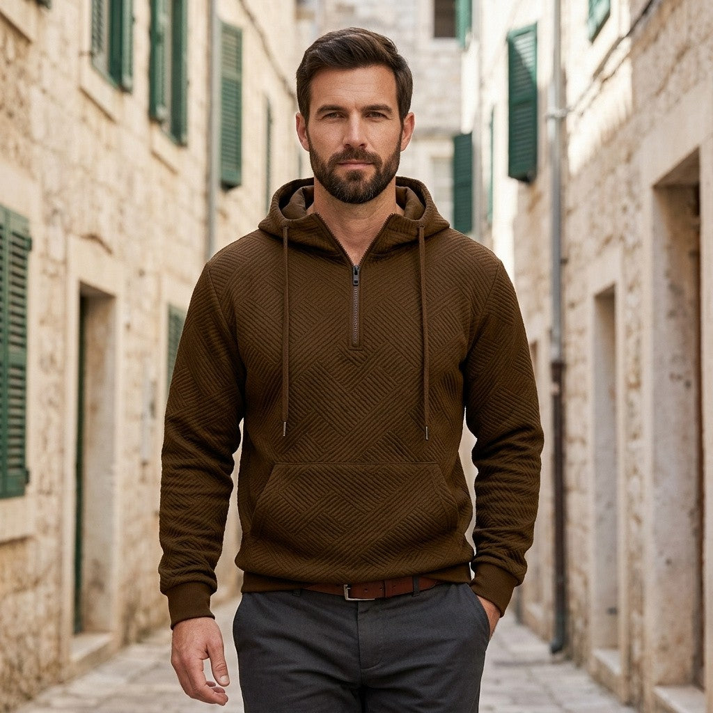 Man wearing the Arosa Textured Quarter-Zip Hoodie in Chocolate Brown with gray trousers on a stone street