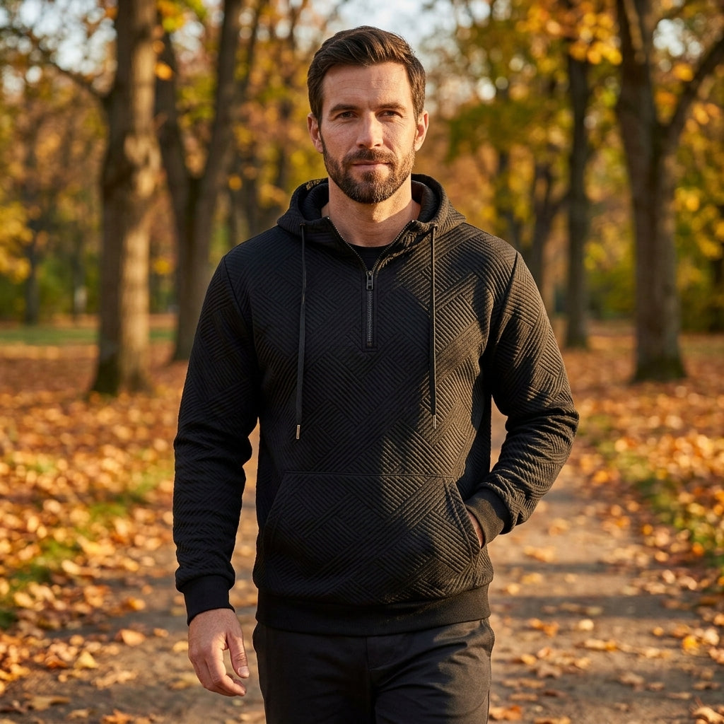 Man wearing the Arosa Textured Quarter-Zip Hoodie in Midnight Black on an autumn walk in the park