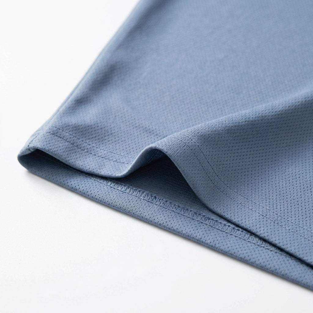 Close-up of the Davos Active Tee hem in Steel Blue, showing the fine micro-mesh knit and double-stitched finish