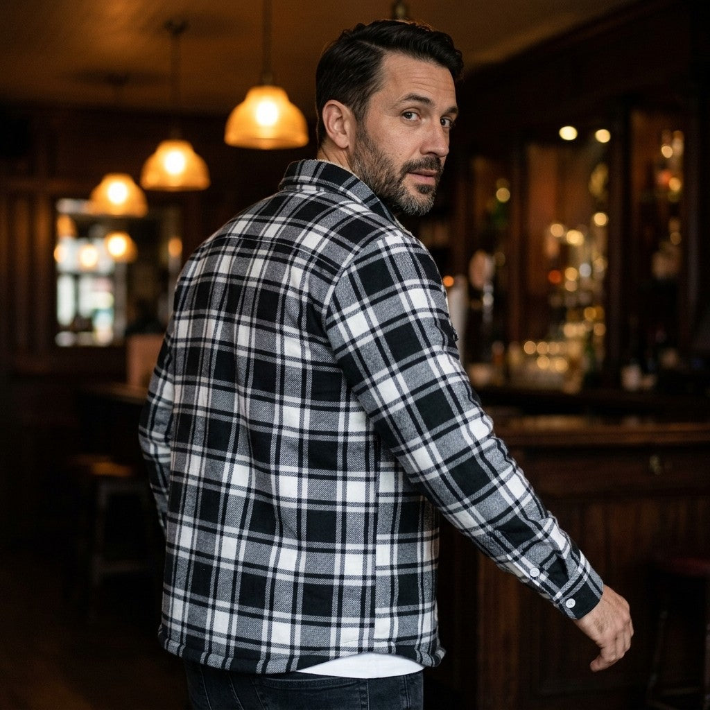 Man wearing the Derrick Sherpa-Lined Plaid Shirt Jacket in black and white plaid on a night out at a pub